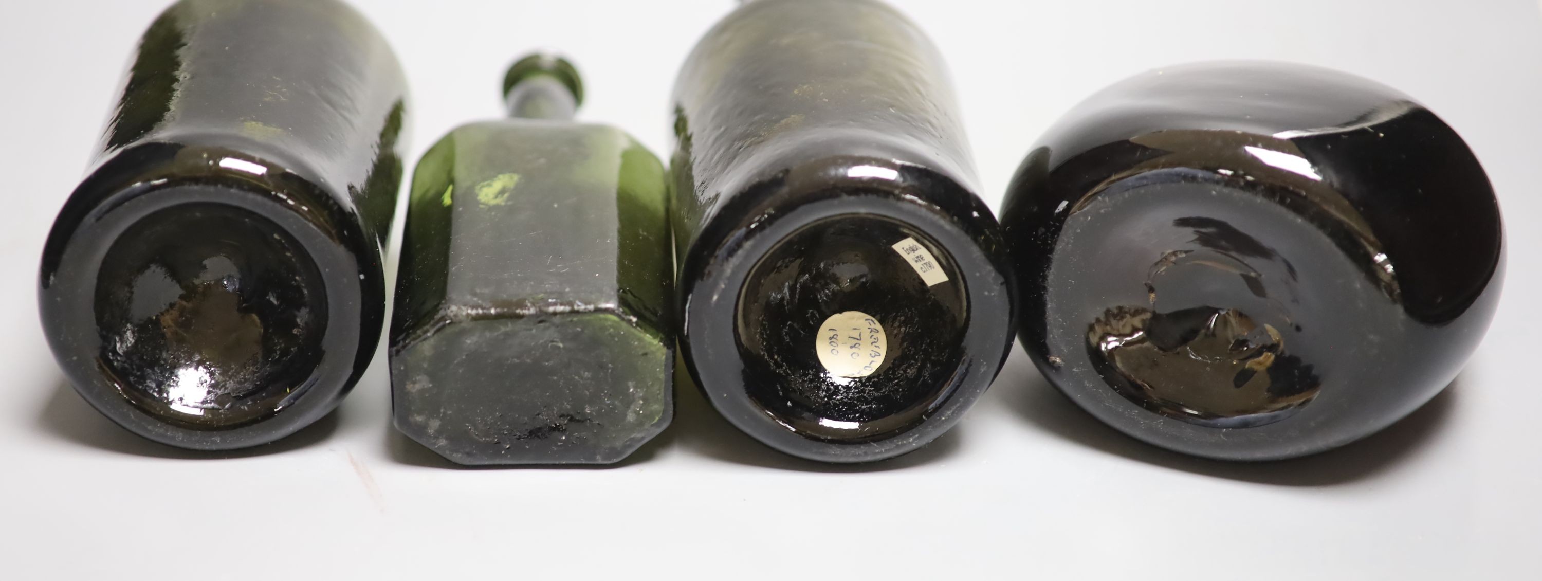 Two English dark green glass wine bottles, late 18th century, a Victorian amber glass hock jug and an early 19th century dark green glass small bottle, tallest 26.5cm (4)